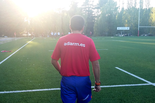 Un árbitro de rugby camina de espaldas con una camiseta de calentamiento de la ADARM.