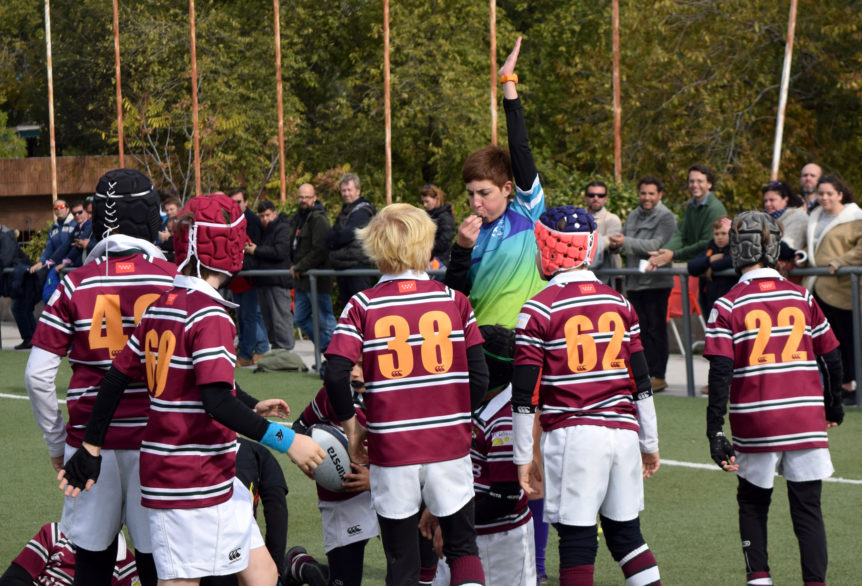 Una árbitro de rugby pita un ensayo rodeada de niños en unas jornadas de rugby gradual.