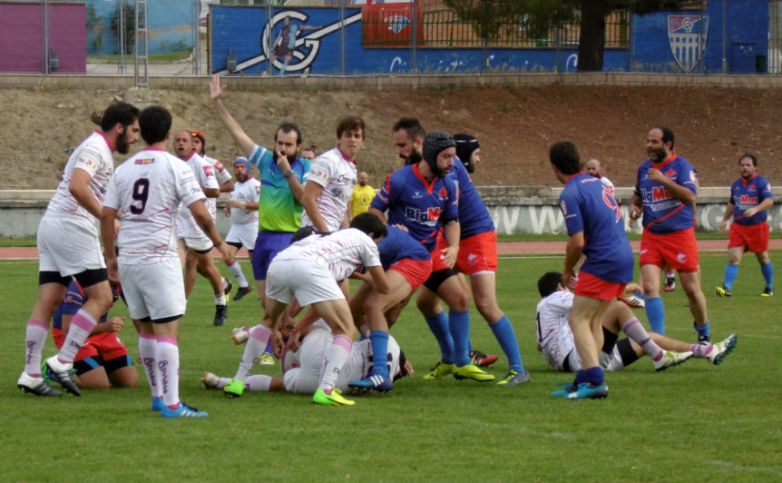 Un árbitro de rugby pita un golpe de castigo entre jugadores.