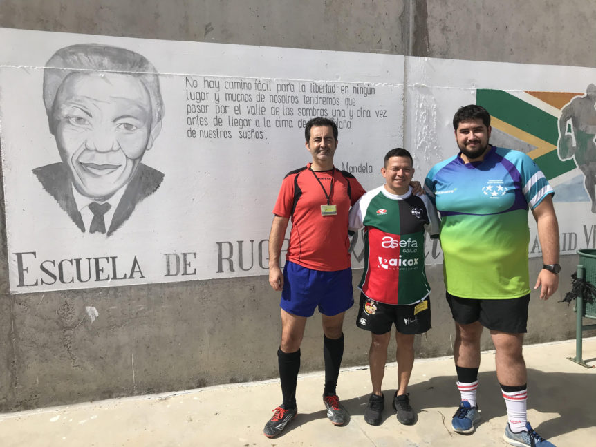 Los tres socios de la ADARM que participaron en la jornada solidaria posan frente al mural en el patio de la prisión de Estremera.